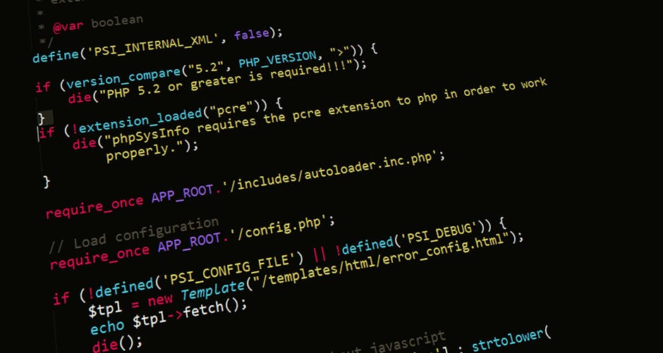 Close-up view of a computer monitor displaying lines of HTML and JavaScript code in a dark-themed editor, with syntax highlighting in blue, white, and teal. The code includes tags for stylesheet links